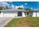 Charming single-story home featuring a two-car garage, and tropical landscaping in a well-maintained lawn at 891 Bayard St, Port Charlotte, FL 33948