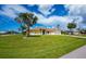 Attractive home with a lush front lawn, mature palm trees, and a convenient two-car garage at 1 Sportsman Cir, Rotonda West, FL 33947