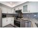 Modern kitchen with stainless appliances, granite counters, white cabinetry and mosaic backsplash at 1 Sportsman Cir, Rotonda West, FL 33947