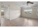 Bright living room with tile flooring, featuring a window with a view of greenery, and access to the bathroom at 10133 Gulfstream Blvd, Englewood, FL 34224