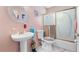 This cozy bathroom showcases a pedestal sink, decorative shower doors, and pink walls at 1041 S Salford Blvd, North Port, FL 34287