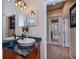 Stylish powder room with vessel sink, black marble countertop, and unique lighting fixtures at 1062 Eagles Flight Way, North Port, FL 34287