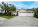 Home exterior with a three-car garage, paver driveway, and tropical landscaping at 1062 Eagles Flight Way, North Port, FL 34287