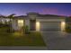 Charming single-story home with a two-car garage, gray shutters, fresh landscaping, and warm exterior lighting at 11088 Pinot Dr, Venice, FL 34293