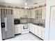 Well-lit kitchen with stainless steel refrigerator, white cabinets, and tiled flooring at 13100 S Mccall Rd # 125, Port Charlotte, FL 33981