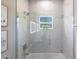Modern bathroom featuring a bathtub with marble tile walls, window, and glass door at 14130 Massey Ave, Port Charlotte, FL 33953