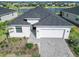 Aerial view of a well-maintained home with a gray roof, paver driveway, lake view, and manicured landscaping at 15069 Anchorage Rd, Punta Gorda, FL 33982