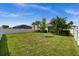 Lush green backyard with palm trees, well-maintained landscaping, and white perimeter fencing at 16176 Lotus Way, Punta Gorda, FL 33982