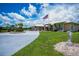 Beautifully landscaped home exterior featuring a circular driveway, mature palms, and a prominent American flag at 17400 White Water Ct, Punta Gorda, FL 33982