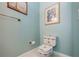 Cozy powder room features a decorative toilet, light blue walls, and beach-themed artwork at 17400 White Water Ct, Punta Gorda, FL 33982