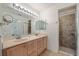 Bathroom featuring a double sink vanity with large mirror, cabinet storage and a tiled walk-in shower at 1812 Birmingham Blvd, Punta Gorda, FL 33980