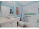 Bright bathroom with blue walls, white vanity and tiled shower/tub combo with decorative glass block window at 1812 Birmingham Blvd, Punta Gorda, FL 33980