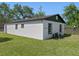 A view of the back of a single story home with white siding and a well-maintained lawn at 2101 W Cherry St, Tampa, FL 33607