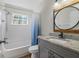 Bathroom features tub with shower and granite vanity with modern round mirror at 2101 W Cherry St, Tampa, FL 33607