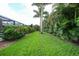 Lush backyard featuring a healthy lawn, privacy landscaping, and view of the screened patio at 23493 Taber Ave, Port Charlotte, FL 33954
