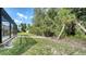 This grassy backyard features tropical foliage and a screened lanai with a pool at 237 Strasburg Dr, Port Charlotte, FL 33954
