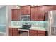 Close-up of kitchen with wood cabinetry, stainless steel appliances, and decorative tile backsplash at 237 Strasburg Dr, Port Charlotte, FL 33954