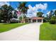 Lovely home with a long driveway, lush green lawn, palm trees, and classic architecture at 2387 Nuremberg Blvd, Punta Gorda, FL 33983