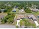 A fenced single Gathering home with a large driveway is surrounded by lush trees in this aerial view at 3138 Darius Ave, North Port, FL 34288