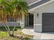 Close-up view of the home's entrance, featuring a dark door, an attached garage, and well-manicured landscaping at 411 Scarlet Sage, Punta Gorda, FL 33955
