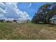 View of the home's back exterior, showing mature trees and ample space in the backyard for recreation at 4424 Baroda Ave, North Port, FL 34287