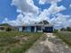 Single story house with blue and white exterior paint, overgrown lawn, and driveway with parked garbage bins at 4424 Baroda Ave, North Port, FL 34287