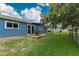 Backyard view with lush grass, a patio set under a blue umbrella, and a sliding door leading to the house at 4583 S Salford Blvd, North Port, FL 34287