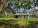 Secluded backyard featuring mature trees and a glimpse of a screened lanai, blending nature with outdoor living at 4609 Jaslo Ave, North Port, FL 34286
