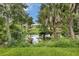 View of a serene backyard with a pond surrounded by lush trees and plants at 5451 Prime Ter, North Port, FL 34286