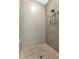 Modern shower features gray tile walls, river rock floor, and rainfall shower head at 5451 Prime Ter, North Port, FL 34286