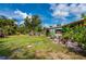 Beautifully landscaped backyard featuring a lush lawn, mature trees, and a charming patio area, creating a serene outdoor space at 611 Bonita Ct, Punta Gorda, FL 33950