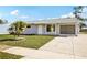 Inviting one-story home featuring a manicured lawn, a small palm tree, and attached garage at 6764 Stardust Ave, North Port, FL 34287