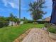 Lush backyard featuring a manicured lawn, decorative landscaping, and a brick patio providing a serene outdoor space at 7292 Mikasa Dr, Punta Gorda, FL 33950