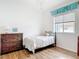 Minimalist bedroom featuring wood floors, a window with blinds, and a decorative wooden dresser at 1007 Comstock St, Port Charlotte, FL 33952