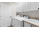 Well-lit laundry room with white cabinetry, a utility sink, and modern washer and dryer at 10316 Hebblewhite, Englewood, FL 34223