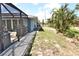 Exterior side view with a screened-in patio featuring outdoor seating, complemented by tropical landscaping and a paved walkway at 107 Sinclair Se St, Port Charlotte, FL 33952