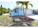 Charming light blue single-story home with an attached garage, complemented by lush tropical landscaping and a brick-paved walkway at 107 Sinclair Se St, Port Charlotte, FL 33952