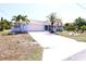 Charming light blue home with an attached garage, complemented by tropical landscaping and a wide driveway at 107 Sinclair Se St, Port Charlotte, FL 33952