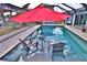 Screened-in pool area with seating under a bright red umbrella, perfect for relaxation and outdoor entertainment at 107 Sinclair Se St, Port Charlotte, FL 33952