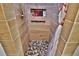 Tiled walk-in shower features built-in shelving and a mosaic pebble floor at 107 Sinclair Se St, Port Charlotte, FL 33952