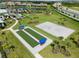 Aerial view of community amenities, including bocce ball courts, a beach volleyball court, and a playground, set among palm trees at 15974 Clear Skies Pl, Bradenton, FL 34211