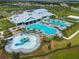 Aerial view of the community pool area, showcasing a splash pad, large pool, ample seating, and beautiful landscaping at 15974 Clear Skies Pl, Bradenton, FL 34211