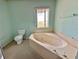 Bathroom featuring a large corner bathtub, toilet, and a window at 1611 Robbins Rd, Nokomis, FL 34275