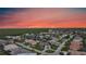 An aerial view captures a residential area with waterfront homes near lush greenery and a stunning sunset at 1801 Los Alamos Dr, Punta Gorda, FL 33950