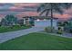 A beautifully landscaped home shows a well-manicured lawn, paved driveway, and three-car garage at dusk at 1801 Los Alamos Dr, Punta Gorda, FL 33950