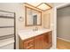 Cozy bathroom features a wood vanity, neutral countertops and a framed mirror with vanity lighting at 2160 Aqui Esta Dr, Punta Gorda, FL 33950