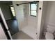Walk-in shower with white tile, window, modern fixtures and view to the main bedroom at 23273 Abeline Ave, Punta Gorda, FL 33980