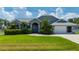 Well-maintained home with vibrant green lawn, mature landscaping, and an arched entryway, exuding curb appeal at 25371 Paladin Ln, Punta Gorda, FL 33983