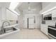 Bright, all-white kitchen featuring stainless steel appliances, tiled floor, and ample storage space at 25371 Paladin Ln, Punta Gorda, FL 33983