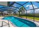 Enclosed pool boasts clear blue water, a tiled edge, and views of a verdant yard and palm trees at 25371 Paladin Ln, Punta Gorda, FL 33983